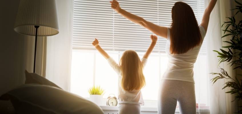 Девочка и мама потягиваются у окна