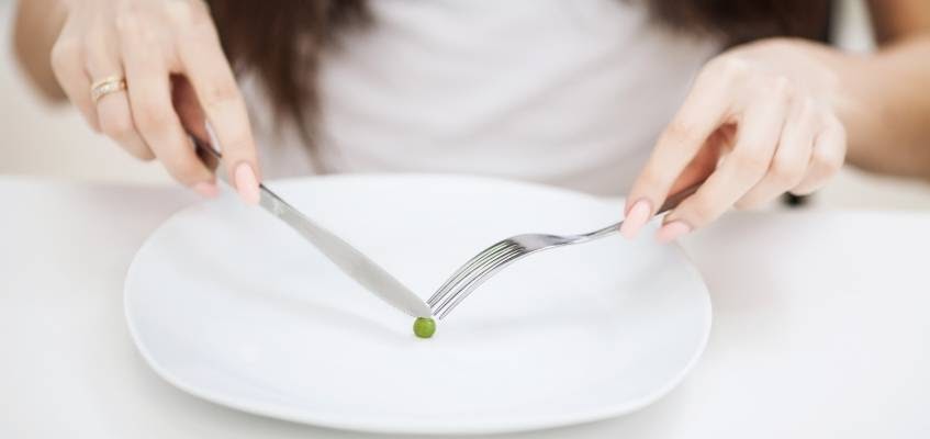 Девушка ест горошину с тарелки