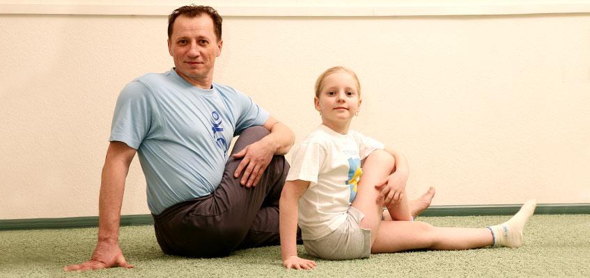 Мужчина и девочка делают йогу