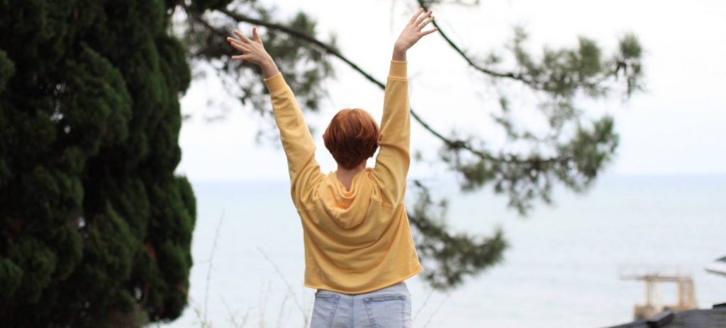 Девушка стоит спиной с поднятыми руками