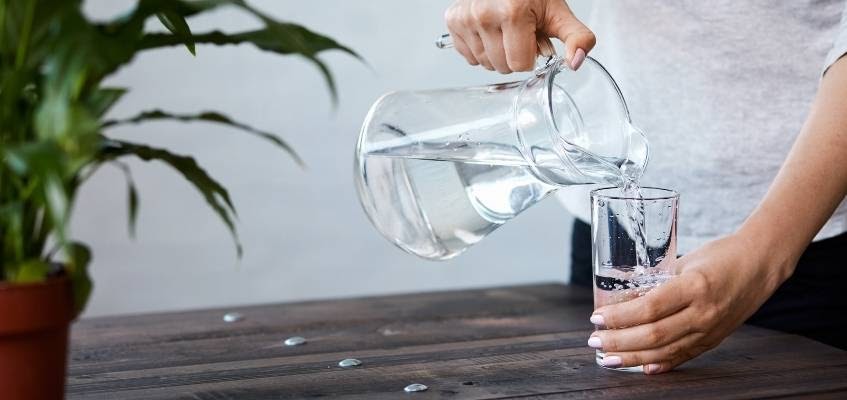 Человек наливают воду в стакан