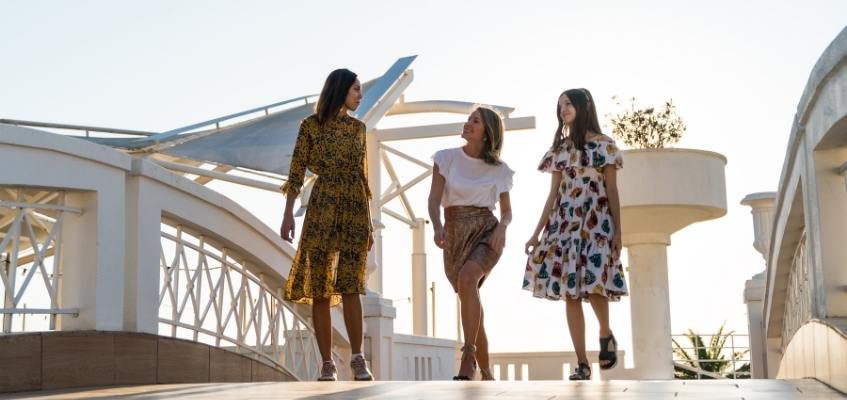 Две девушки и ребенок переходят через мост