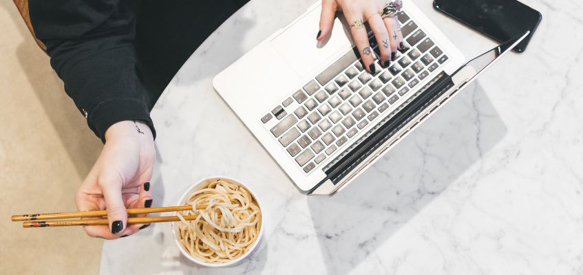 Женщина ест за ноутбуком