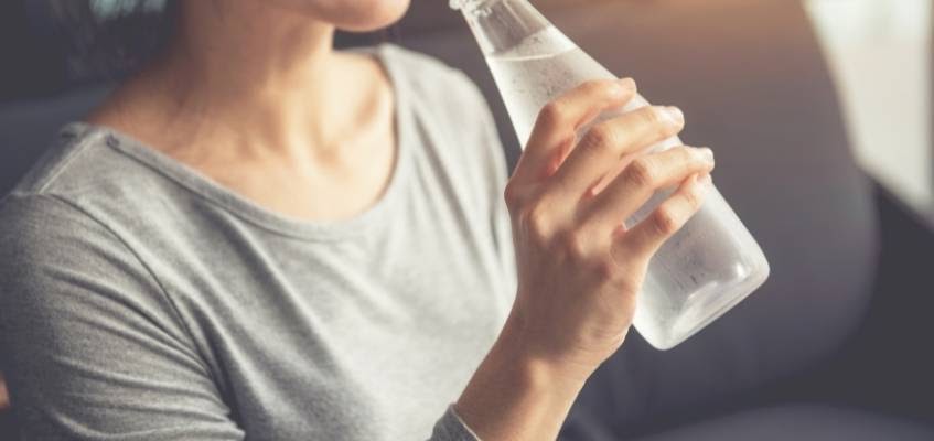 Девушка пьет из бутылки холодную воду